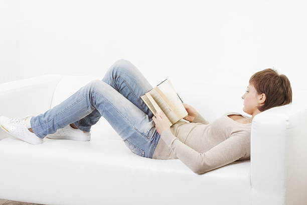 istock Young woman reading book laying on back 102750960