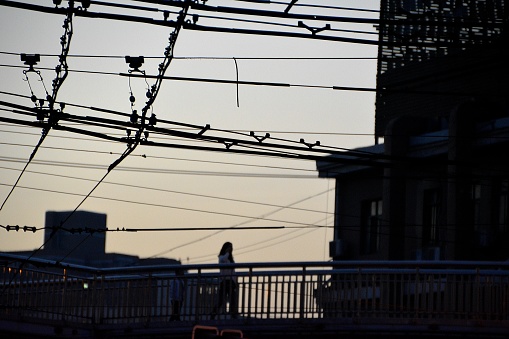 Girl walking on a footbridge surrounded by cables at sunset in Hongkou district, Shanghai, China