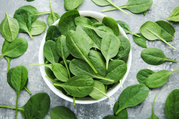 Spinach leafs in bowl on grey wooden table stock photo