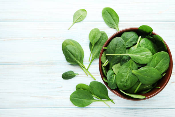 istock Spinach leafs in bowl on wooden table 1027533956