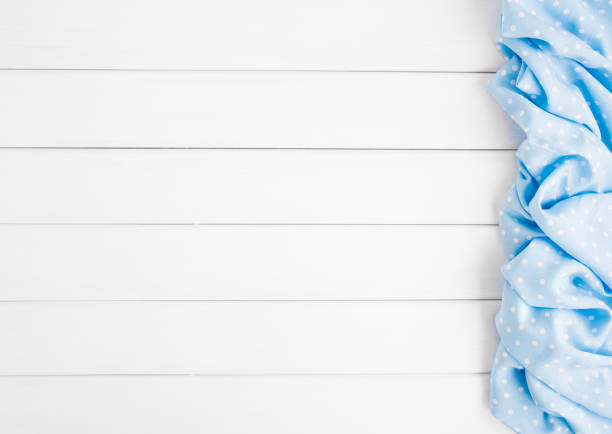 istock Light blue polka dots folded tablecloth over bleached wooden table. Top view image. Copyspace for your text. 1027537052