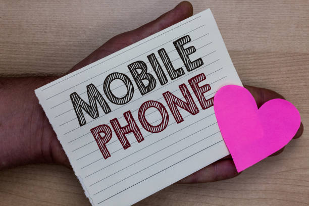 istock Word writing text Mobile Phone. Business concept for A handheld device used to send receive calls and messages Man holding piece notebook paper heart Romantic ideas messages feelings 1027540416