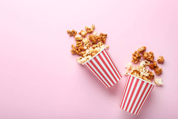 Caramel popcorn in paper cups on pink background stock photo