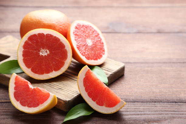 istock Ripe grapefruits with green leafs on brown wooden table 1027546382