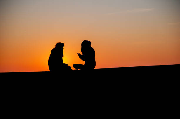 istock confidences between two teenagers at sunset 1027546494