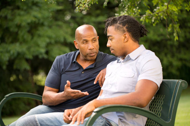 mature man mentoring and giving advice to a younger man. - teenager parent father son imagens e fotografias de stock