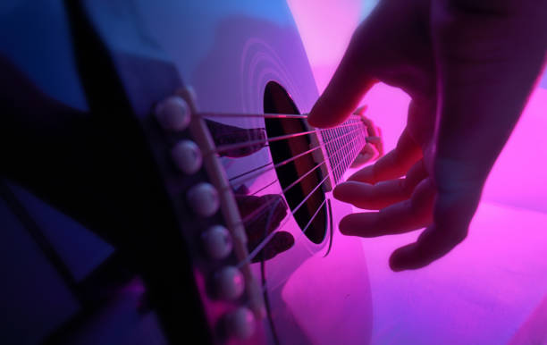 guitarra acústica interpretada por una chica y luces de colores - plucking an instrument fotografías e imágenes de stock