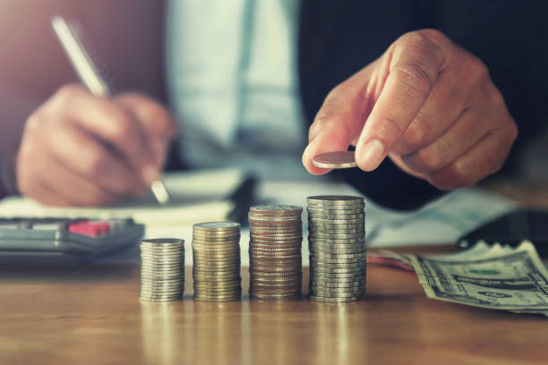 istock concept saving money. hand holding coins putting stack on table in office 1027564772