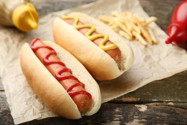 cachorro-quente com mostarda e ketchup na mesa de madeira - cooked studio shot close up sausage - fotografias e filmes do acervo