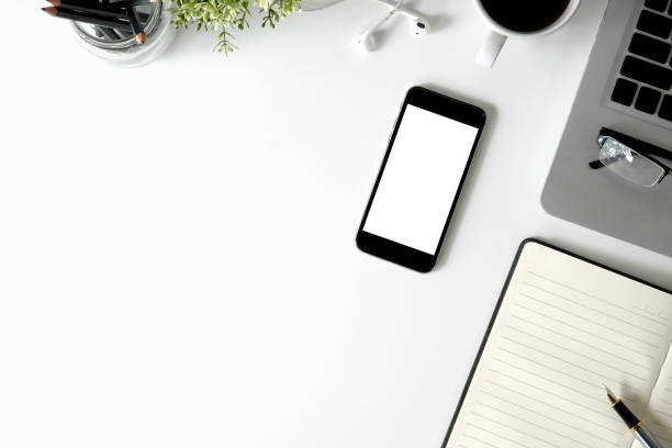 istock Mockup smartphone on office desk with laptop and notebook paper, Copy space mockup mobile phone with top view. 1027575738