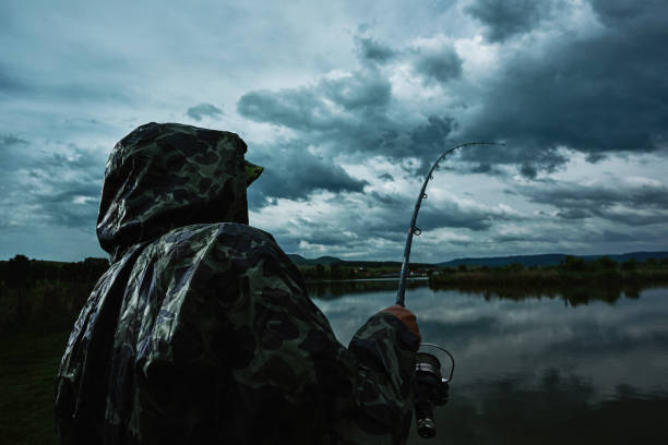 senior man in rainy day fishing with rain coat on him.