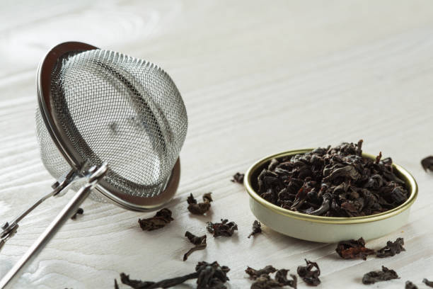 chinese  black tea and brew sieve on white wooden table - garble imagens e fotografias de stock