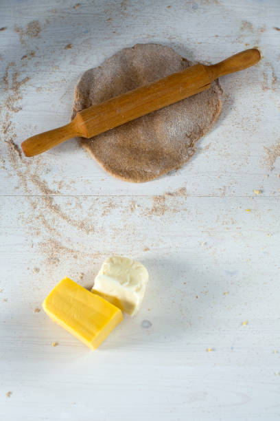 istock dough for pizza rolling on a wooden white table sprinkled with flour with yellow and white cheese 1027584128