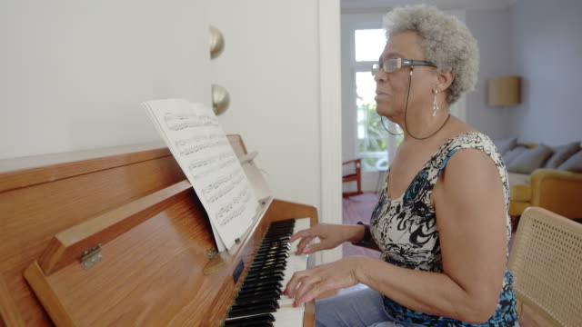 Senior woman playing piano at home