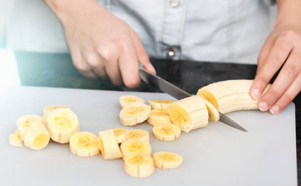 Hands slicing banana in kitchen