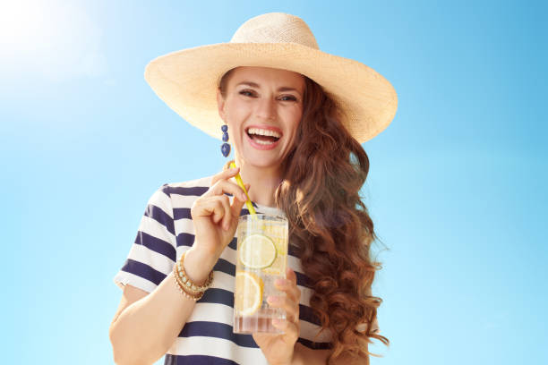 istock happy modern woman against blue sky with refreshing cocktail 1027623816