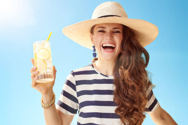 istock cheerful modern woman against blue sky with refreshing cocktail 1027623824
