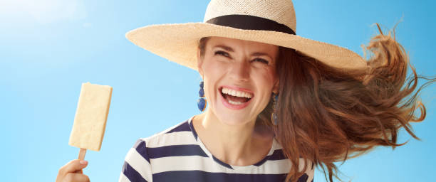 istock woman against blue sky with ice cream on stick 1027624042
