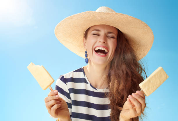 istock smiling woman against blue sky with two ice cream on stick 1027624152