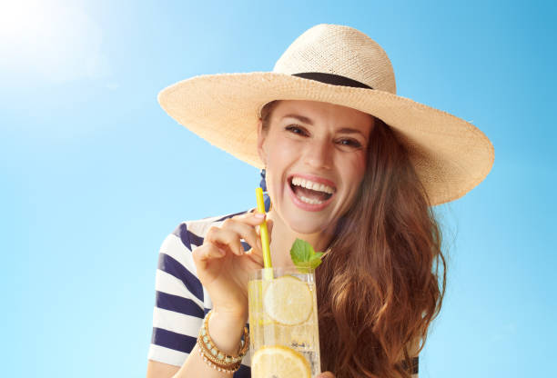 istock smiling modern woman against blue sky with refreshing cocktail 1027624328