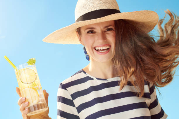 istock smiling modern woman against blue sky with refreshing cocktail 1027624332