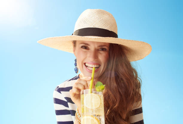 istock smiling woman against blue sky drinking refreshing cocktail 1027627716