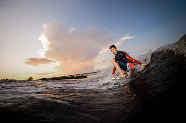 istock Side view active male wakeboarder riding on the bending knees on the board 1027632720