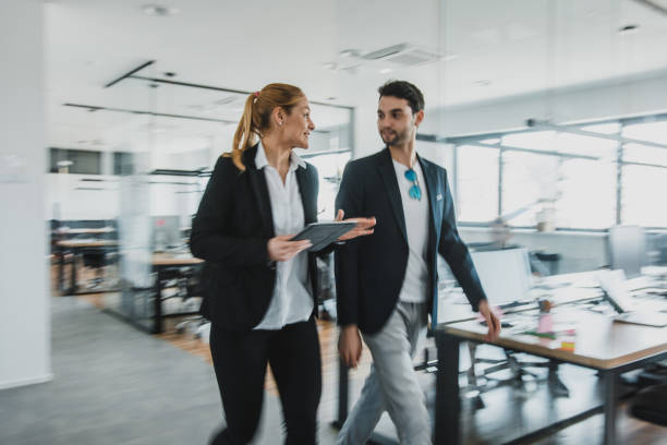 istock Two colleagues walking in the office and talking about their business plans 1027634334