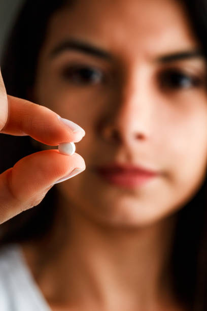 mujer joven hispana dispuesta a tomar la píldora de anticoncepción de emergencia - pill human pregnancy capsule women fotografías e imágenes de stock