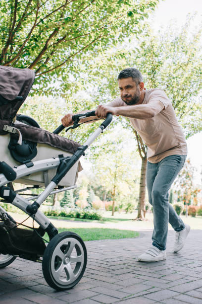 istock father walking with heavy baby carriage in park 1027646502