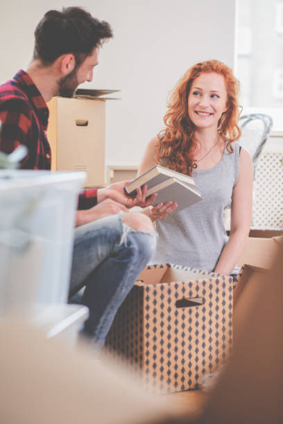 istock Smiling couple packing stuff into carton boxes while moving-out 1027649402