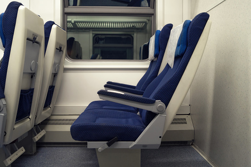 Empty chairs in the train side view. The interior of the railway wagon, carriage with blue seats.
