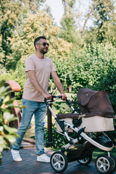 istock father walking with baby carriage in park 1027654262