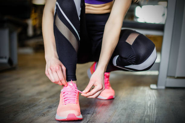 istock Young woman tying shoelaces before training in gym. 1027659560