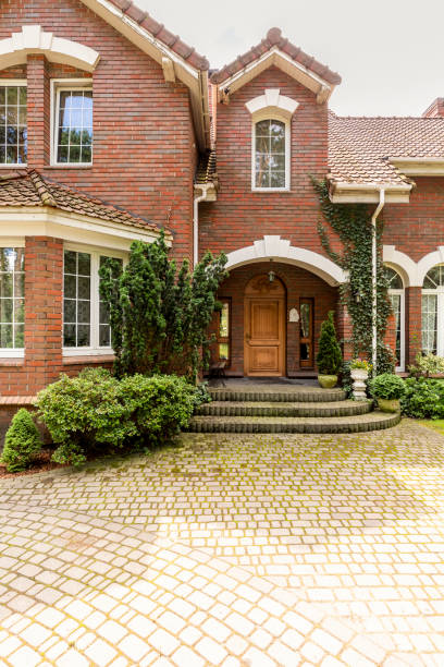 A welcoming entryway with ornamented wooden door, side windows and evergreens in a red brick stylish house. Empty cobbled path in a front. A welcoming entryway with ornamented wooden door, side windows and evergreens in a red brick stylish house. Empty cobbled path in a front. hampton virginia photos stock pictures, royalty-free photos & images