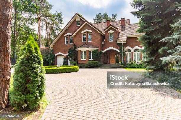 Large Cobbled Driveway In Front Of An Impressive Red Brick English Design Mansion Surrounded By Old Trees Stock Photo - Download Image Now