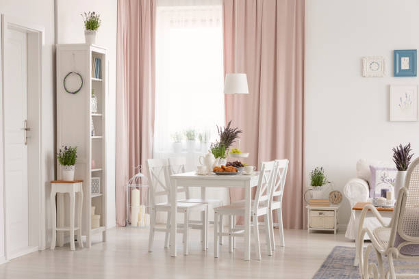 istock White flat interior with window with curtains, fresh lavender, dining table with breakfast and posters on wall in the real photo 1027663312