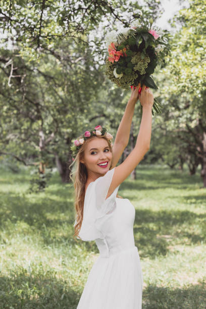 istock beautiful smiling young bride throwing wedding bouquet in park 1027665844