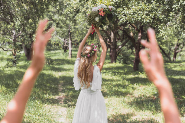 enfoque selectivo de la hermosa joven novia lanzando el ramo de la boda en parque - flower toss fotografías e imágenes de stock