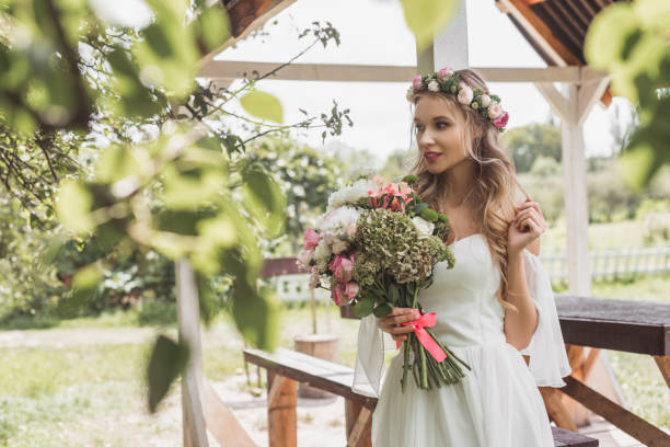 istock beautiful tender young bride holding wedding bouquet and looking away 1027673140