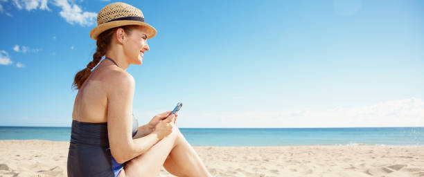 istock happy woman with smartphone looking into distance on seacoast 1027673482