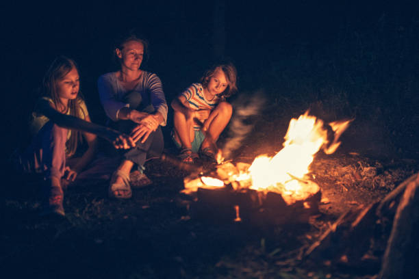 istock Mother sitting next to the campfire with her children 1027673982