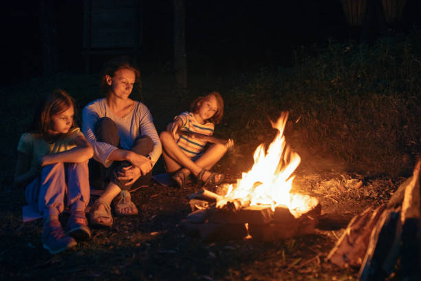 istock Mother sitting next to the campfire with her children 1027674056