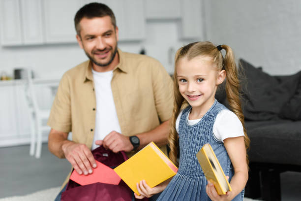 istock selective focus of smiling father helping little daughter packing backpack for first day at school, back to school concept 1027677556
