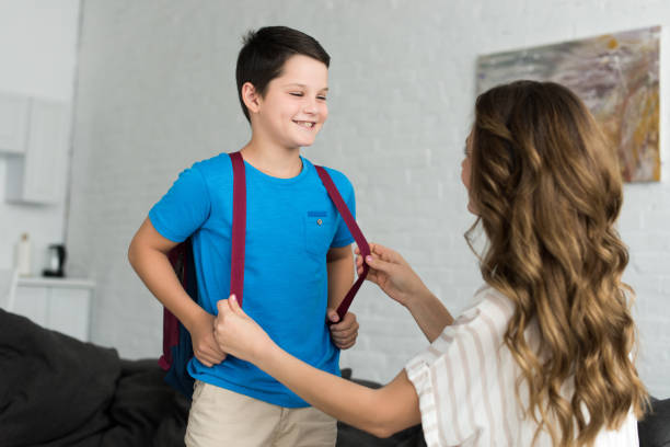 istock partial view of mother and smiling boy with backpack at home, back to school concept 1027677592