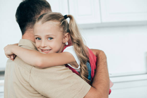 istock father and smiling daughter with backpack hugging each other in kitchen at home, back to school concept 1027677750