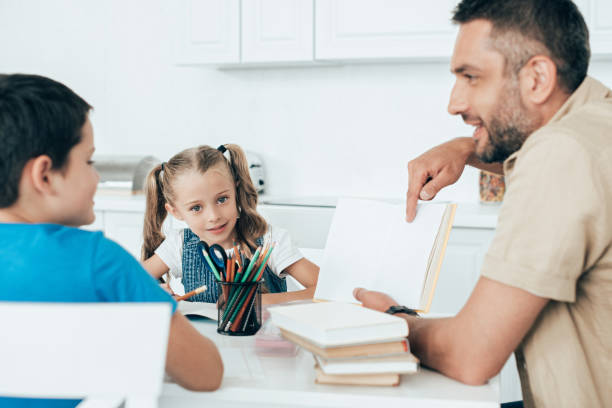 istock smiling father and kids doing homework together at home 1027677766