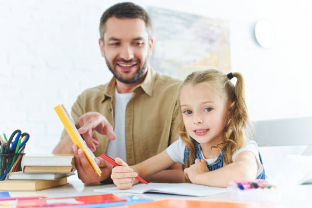 istock smiling father and little daughter doing homework together at home 1027680512