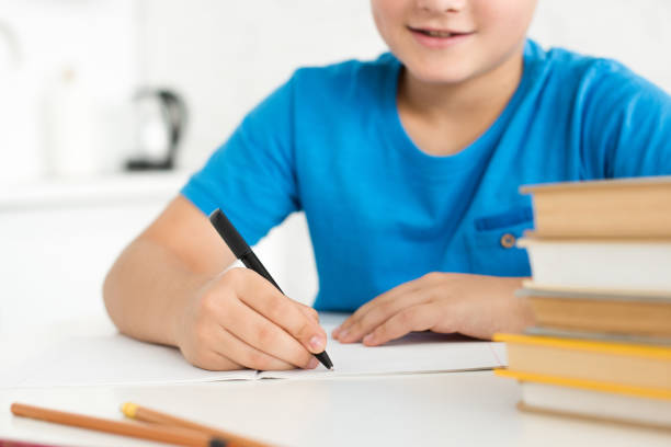 istock partial view of boy writing in copybook while doing homework at home 1027680566