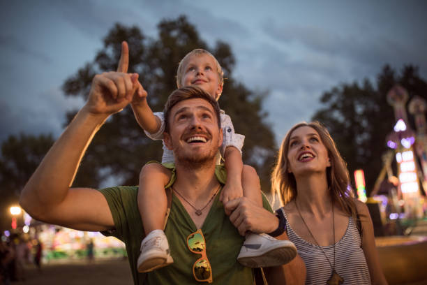 Family enjoy on summer festival Family with one child outdoors on summer festival. Father carrying son on shoulders, they enjoy in festival entertaining amusement park photos stock pictures, royalty-free photos & images